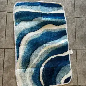 Alfombra con ondas azules y blancas sobre baldosas grises