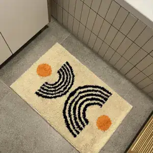 Alfombra crema con arcos negros y círculos naranjas sobre suelo gris