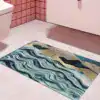 Alfombra de baño azul con diseño abstracto de ondas y tonos dorados.