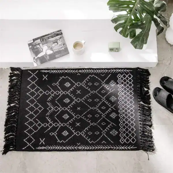 Alfombra de baño bereber negra con bordes de flecos y diseño geométrico blanco.