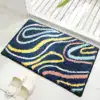 Alfombra baño con diseño ondas multicolores sobre fondo negro.