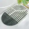 Alfombra de baño ovalada con diseño geométrico en negro y blanco.