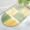 Alfombra de baño ovalada con diseño geométrico en verde y amarillo.