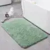Alfombra de baño suave de color verde menta, textura peluda, en baño con azulejos grises.