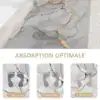Alfombra de baño con diseño de mármol gris y detalles dorados, mostrando absorción óptima en 1, 3 y 5 segundos.