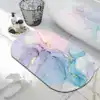 Alfombra de baño con diseño abstracto en tonos pastel y dorado, colocada junto a una bañera.
