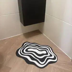 Alfombra pequeña de ondas en blanco y negro en la esquina de un baño