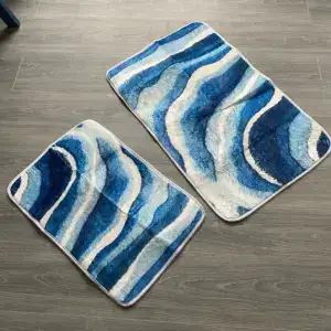 Dos alfombras de baño con vetas azules y blancas sobre suelo gris